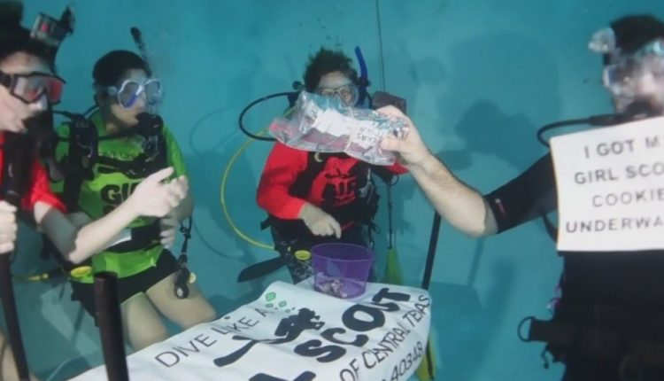 Scuba diving girl scouts sell cookies while sending a message